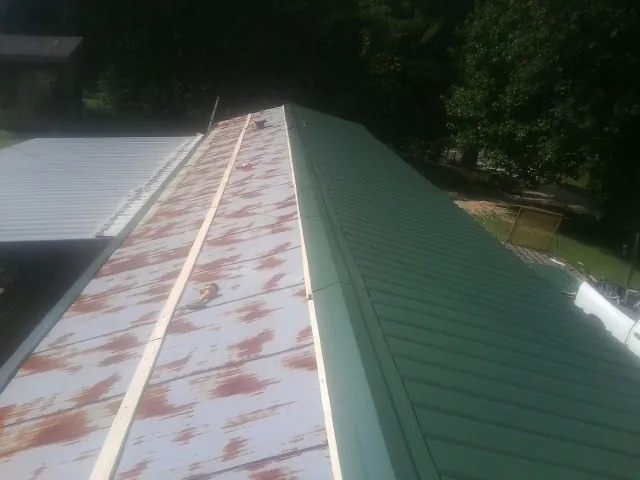 Old rusted panels beside newly installed green metal roofing — Wind Damage Roof Repair by Roofing Brothers in Union Hall