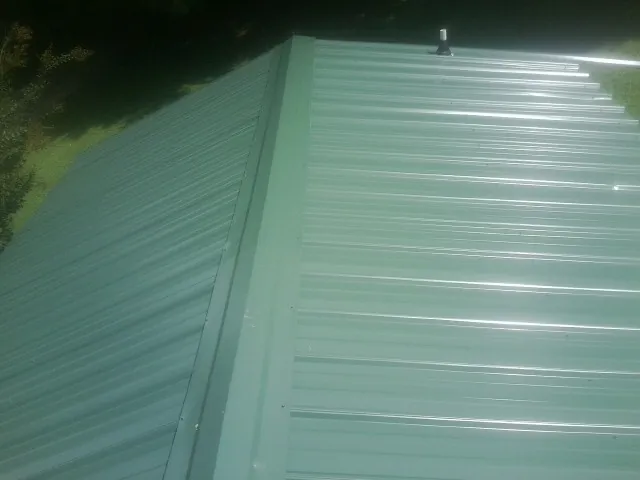 New green metal panels meeting at the ridge of a roof — Flat Roof Repair work by our crew in Union Hall