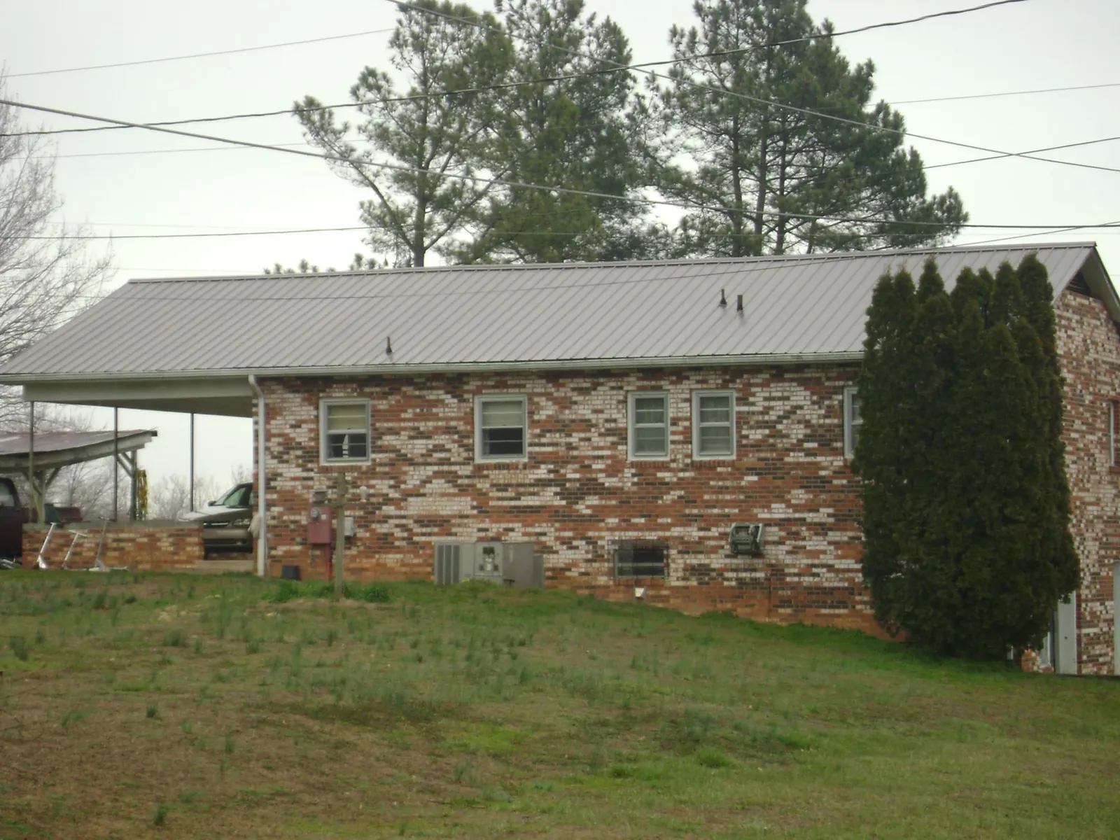 Gray metal roof on a brick split level home with a carport in Union Hall